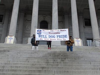 Supporters of South Carolina State University hold up a banner at a Statehouse rally against a proposal to close South Carolina State University on Feb. 16, 2015, in Columbia, S.C. Supporters are now suing the state over unequal funding. (AP Photo/Jeffrey Collins)