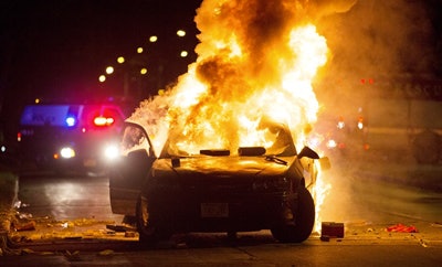 A car burns as a crowd of more than 100 people gathers following the fatal shooting of a man in Milwaukee, Saturday, Aug. 13, 2016 (Calvin Mattheis/Milwaukee Journal-Sentinel via AP).