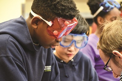 Two UMB CURE scholars from Southwest Baltimore Charter School don goggles for a chemistry experiment with their mentor.