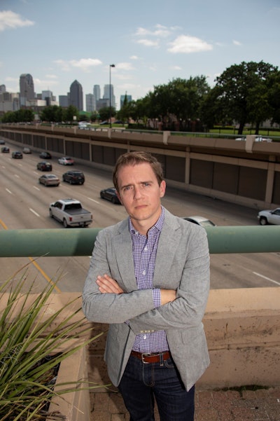 Collin Yarbrough stands on an overpass above Dallas’ Central Expressway. Freedman’s Cemetery is in the background.