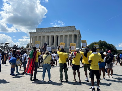 Advocates to cancel student debt pose in front of the Lincoln Memorial during the 60th anniversary of the March on Washington.